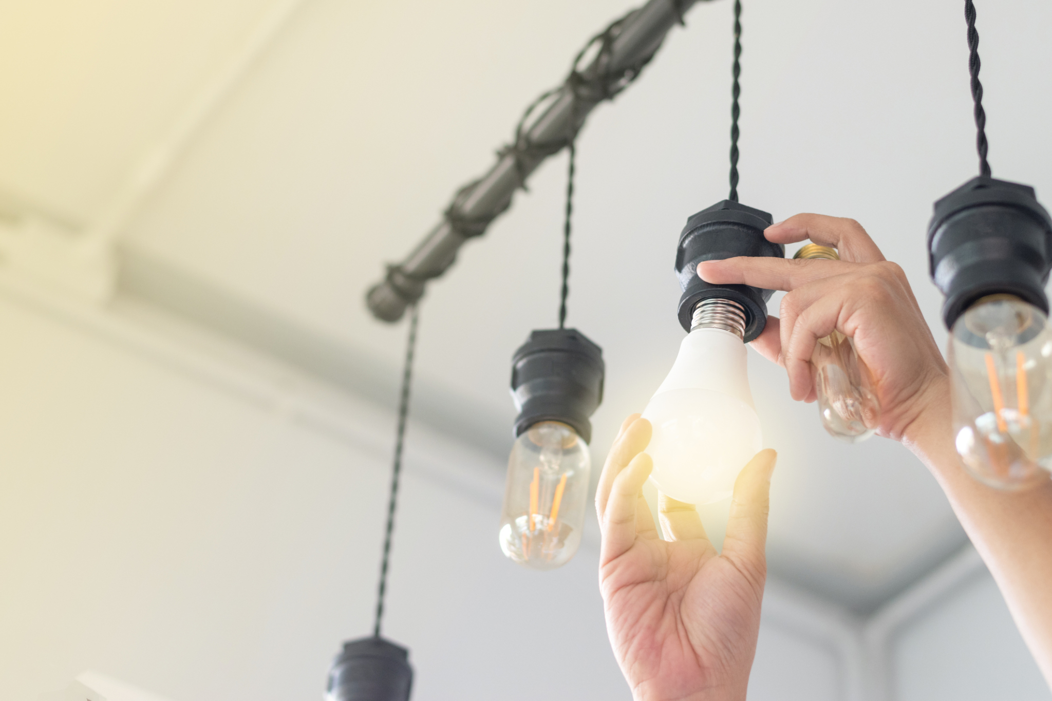 Person changing compact-fluorescent (CFL) bulbs with new bulb.